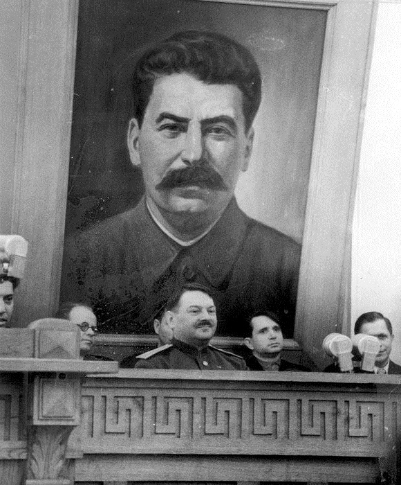 Жданов на фоне портрета Сталину